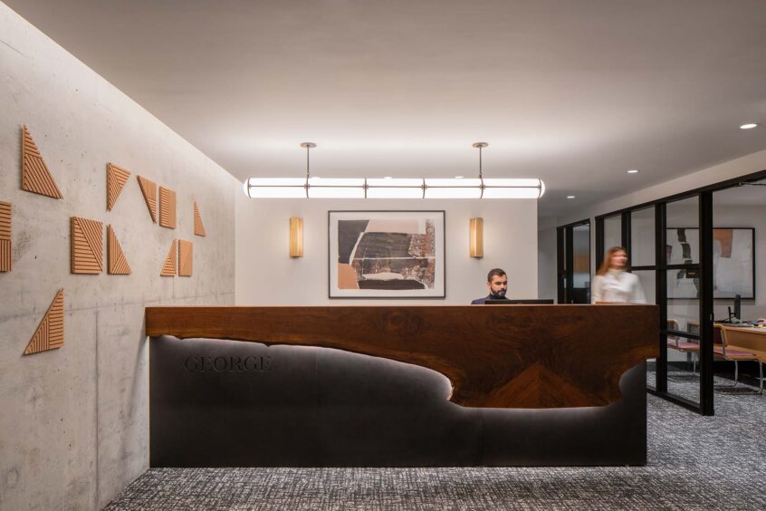 A tastefully-lit desk for an apartment, featuring formed concrete and wood paneling.