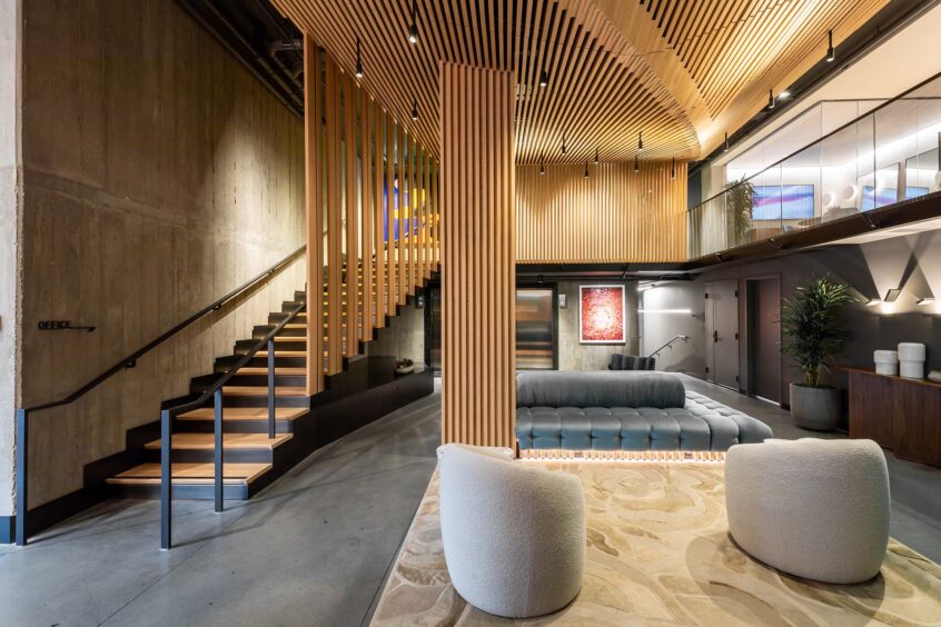 The open lobby of an apartment building, with several seats available and expansive wood paneling